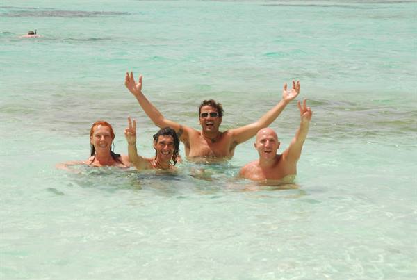 Four friends celebrating with raised arms in clear turquoise water