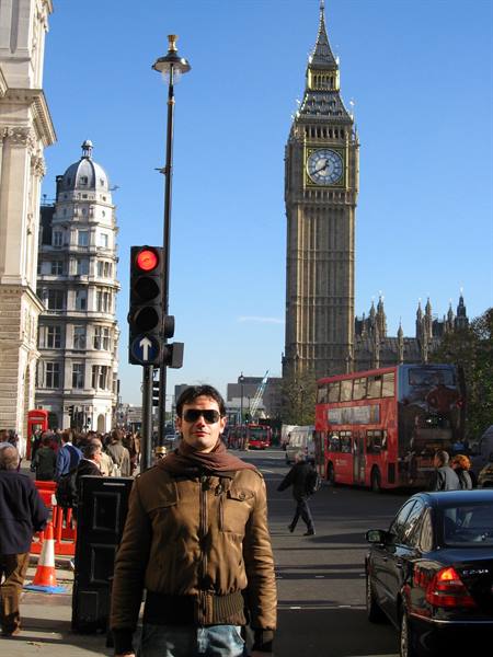Tourist in sunglasses in front of Big Ben and a red London bus