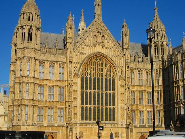 Gothic stone facade with tall arched window, Westminster, under blue sky