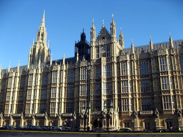 Palace of Westminster in sunlight, Gothic stone facade against clear blue sky