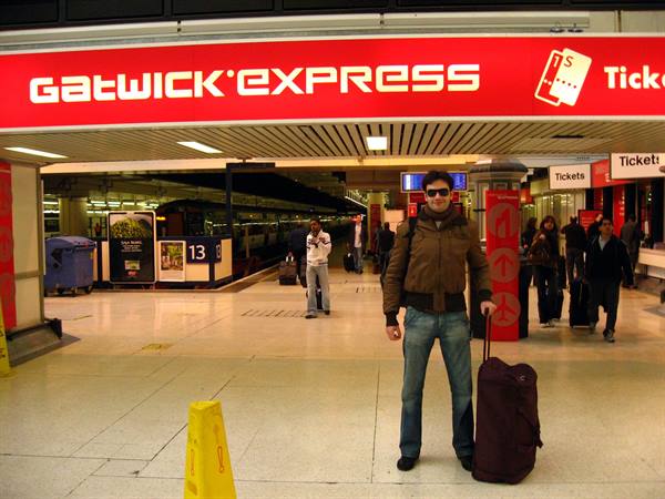 Traveler with rolling bag under the red Gatwick Express sign, train station