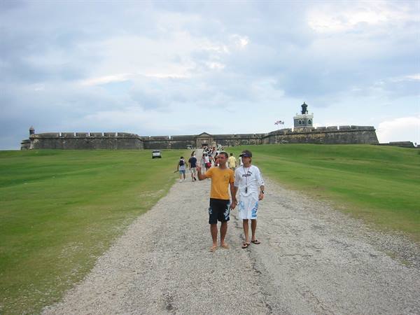 Tourists walking toward San Felipe del Morro fortress across the grassy lawn