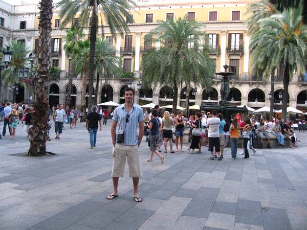 Smiling tourist in striped shirt on La Rambla, Barcelona, among palm trees