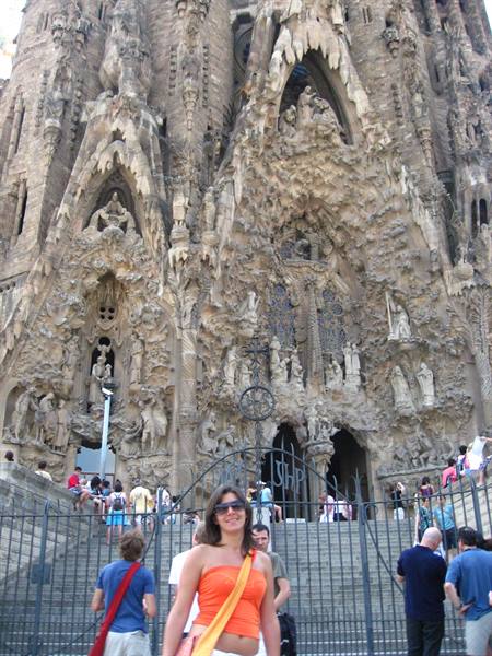 Woman in orange top in front of the Sagrada Família facade in Barcelona