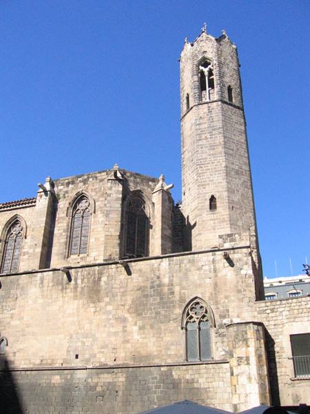Stone bell tower of Barcelona Cathedral against a blue sky