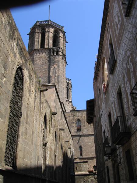 Gothic stone bell tower between old buildings, blue sky, Barcelona's Gothic Quarter