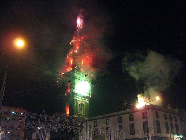 Red fireworks light up the baroque bell tower at night