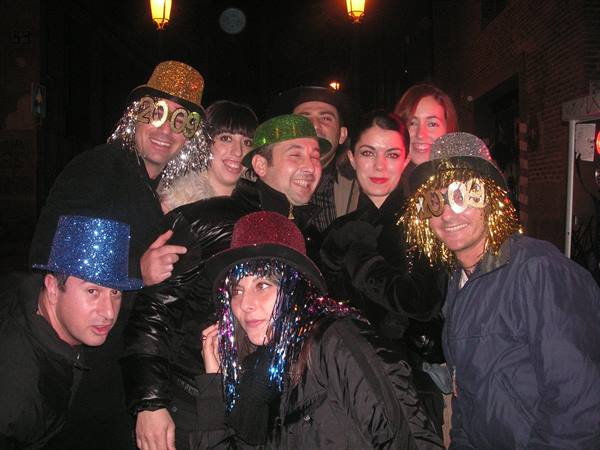 Friends in glitter hats and tinsel glasses celebrating together on a night street