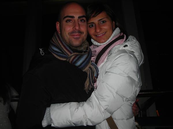 Couple hugging at night, he wears striped scarf, she wears white down jacket