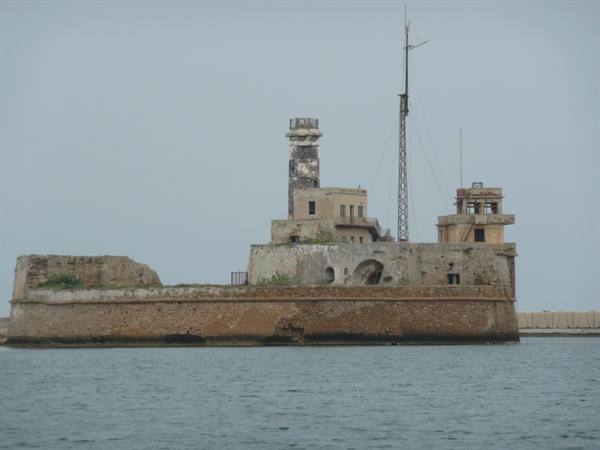 Abandoned stone sea fort with old lighthouse tower and radio antenna