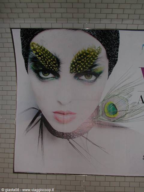 Advertising poster with a woman's face, feather eyebrows and peacock feather