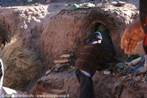 Man working beside an earthen kiln dug into raw mud