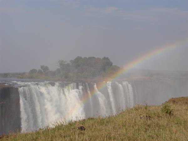 Rainbow over Victoria Falls, water spray above dry grass