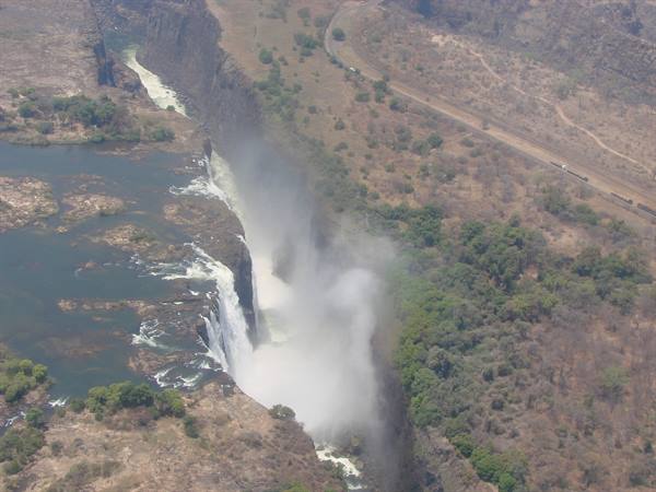 Zambezi river falling into rocky gorge, white mist rising among greenery