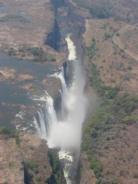Aerial view of Victoria Falls, white water plunging into the misty rocky gorge