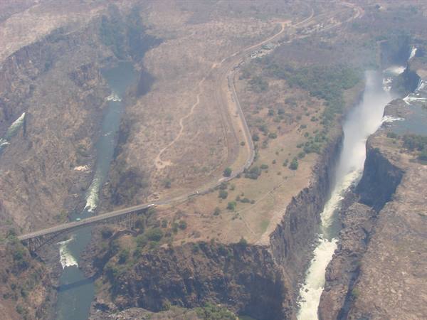 Aerial view of Victoria Falls, white spray rising in the gorge, bridge over Zambezi