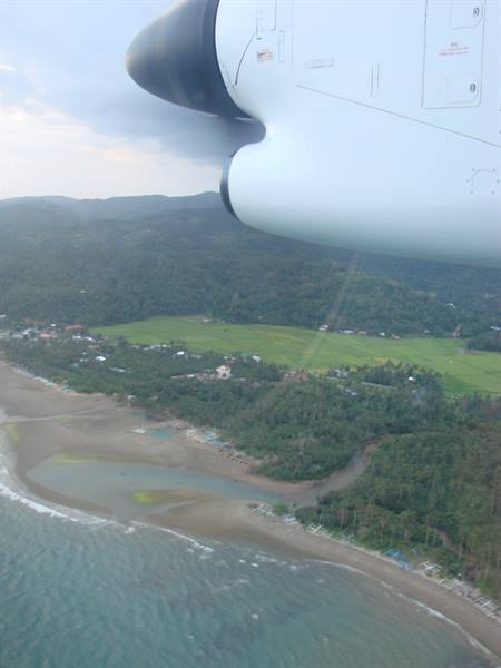 Aircraft engine over the coast, sandy beaches, green fields and forested hills