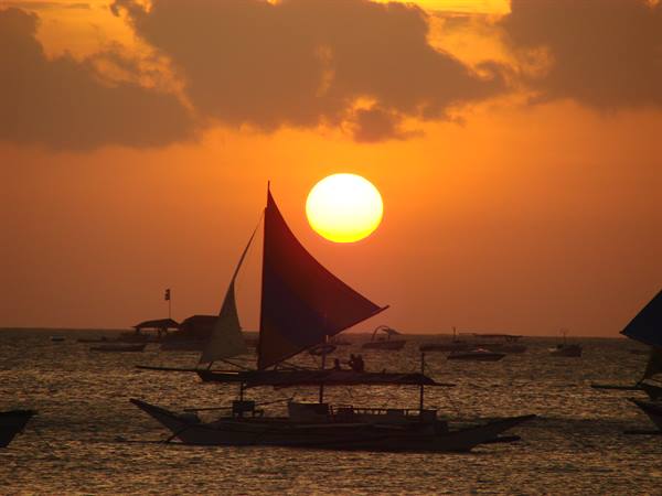 Sailboat silhouette on the sea with the low sun