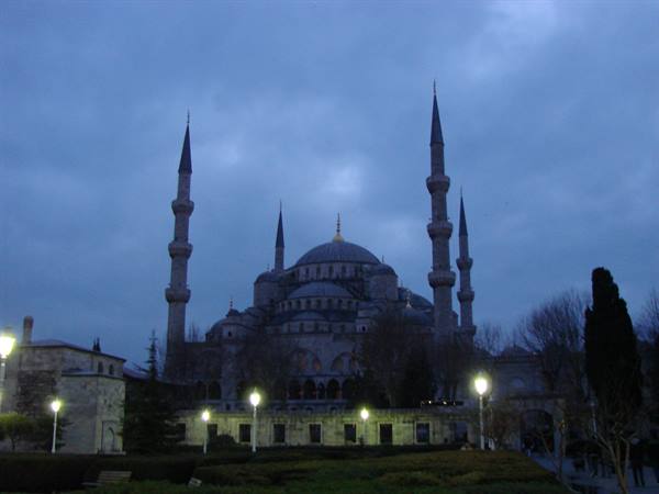 Street lamps lit before the Blue Mosque in Istanbul under an evening cloudy sky