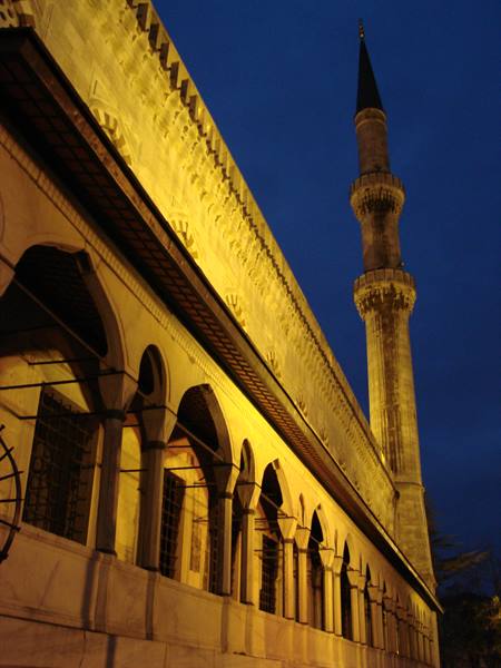 Stone arcade arches and minaret lit at night, Blue Mosque Istanbul
