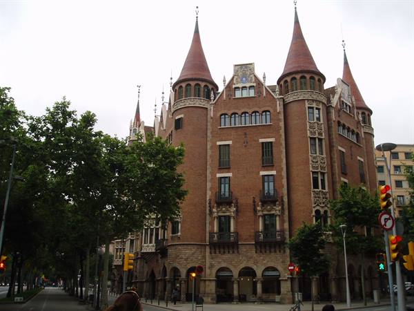 Casa de les Punxes in Barcelona, red brick towers with conical spires under grey sky