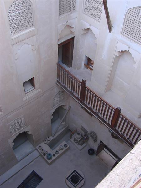 Inner courtyard of a traditional plaster house with wooden balcony and pottery