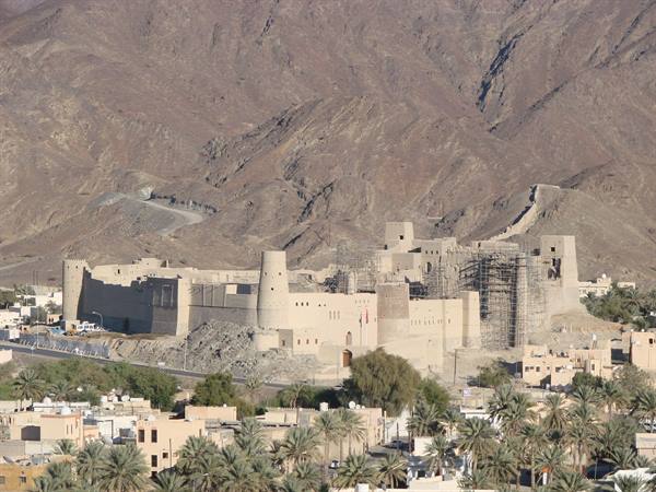 Bahla Fort, mud-brick walls among palm trees and arid mountains