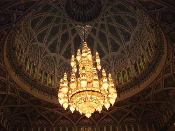 Illuminated golden chandelier beneath the decorated dome of Sultan Qaboos Grand Mosque