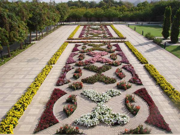 Geometric flowerbeds in red, white and yellow among brick paths in Delhi garden