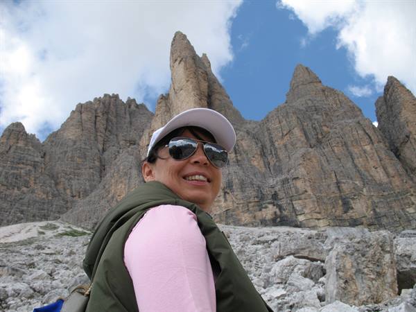 Woman in white cap and sunglasses in front of jagged Dolomite rock spires
