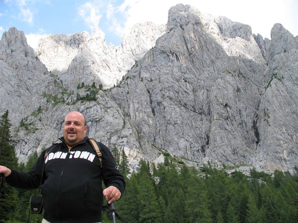 Hiker with poles in front of Dolomites rock walls