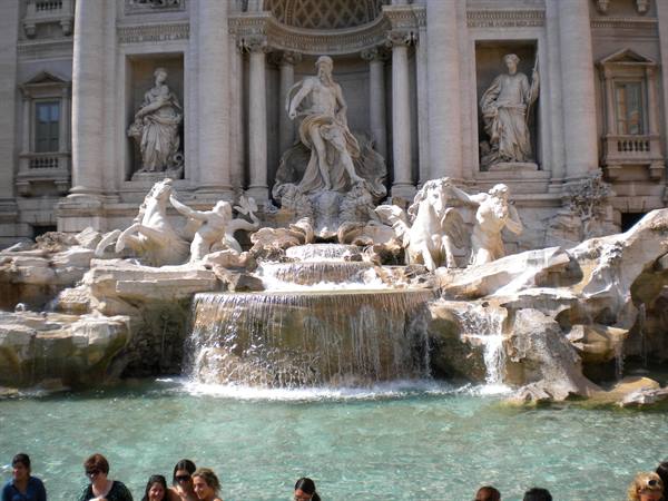 Tourists in front of Rome's Trevi Fountain, marble statues and flowing water