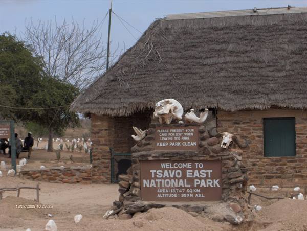 Welcome sign at Tsavo East National Park, stone hut with thatched roof and animal skulls