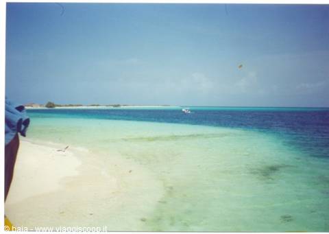 White sand beach, clear turquoise water, boat in the distance