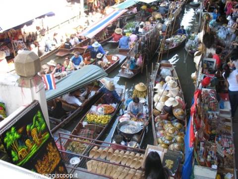 Floating market: wooden boats with fruit and straw hats along the canal