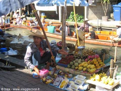 Fruit vendor at Damnoen Saduak floating market, boats full of tourists