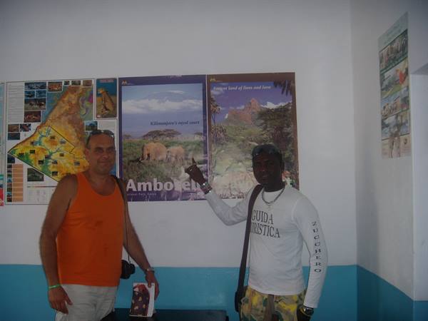 Tour guide points at an Amboseli poster with elephants on the wall