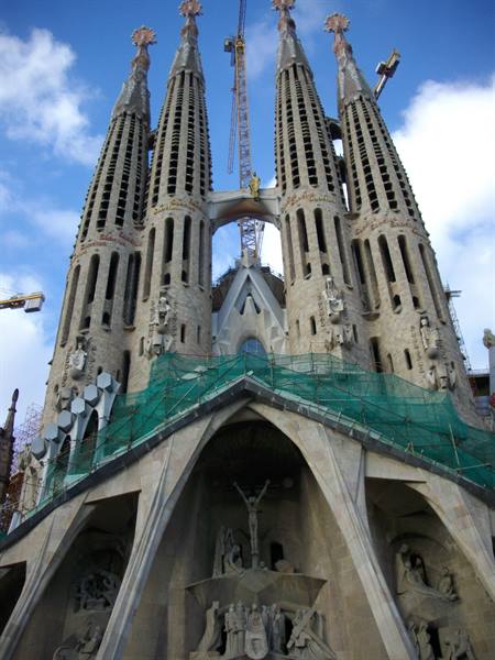 Sagrada Família in Barcelona, stone spires with scaffolding and cranes, blue sky