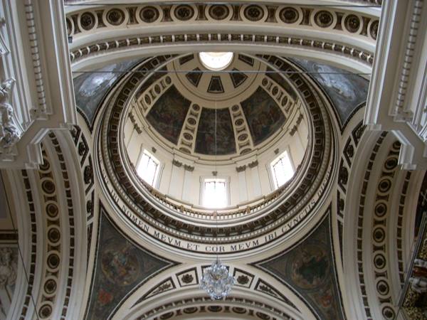 Frescoed dome of a baroque church, lit windows, Latin inscription and crystal chandelier
