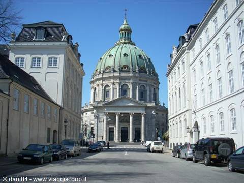 Frederik's Church in Copenhagen, green copper dome between white buildings and parked cars