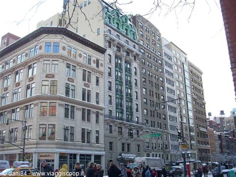 Stone and brick buildings on Broadway, pedestrians and traffic under winter sky