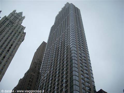 Glass and stone skyscraper towering among towers under grey sky, New York