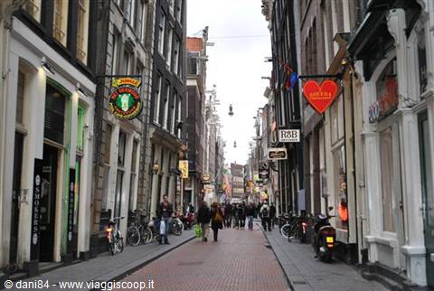 Cobblestone street with historic buildings, coffee shop signs and parked bicycles in Amsterdam