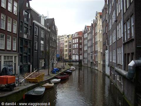 Boats moored along an Amsterdam canal between narrow brick houses
