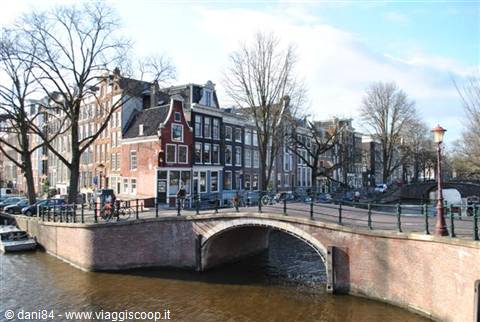 Brick bridge over Amsterdam canal among Dutch houses and bicycles