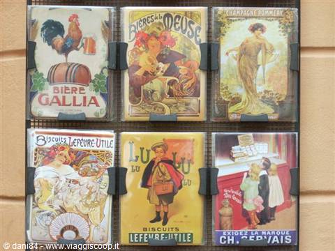 Six vintage enamel advertising signs on a black grid, beer and biscuit ads