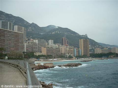 Monte Carlo seafront, high-rise buildings on the mountainside, waves on breakwaters