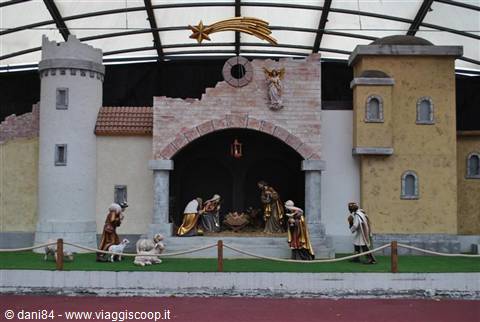 Nativity scene with figurines, masonry houses, tower and golden comet under a canopy