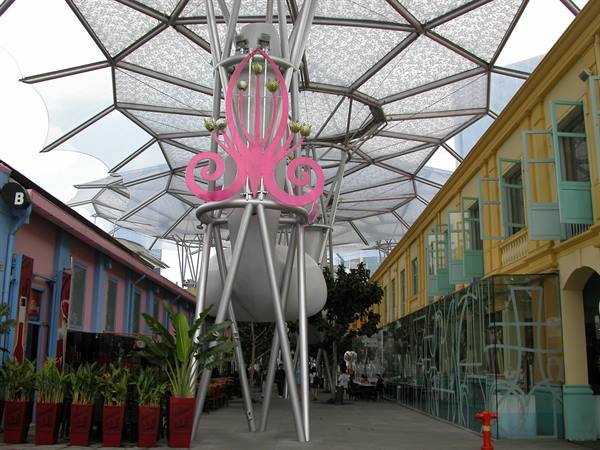 Pink sculpture under glass and steel canopy among colorful shophouses at Clarke Quay