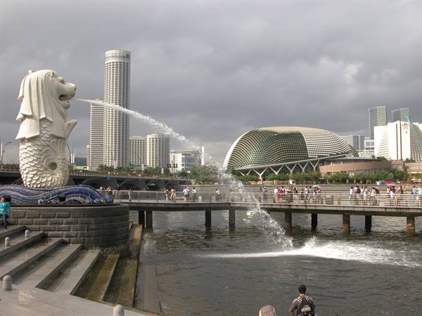 The Merlion statue in Singapore spouts water into the bay under cloudy sky